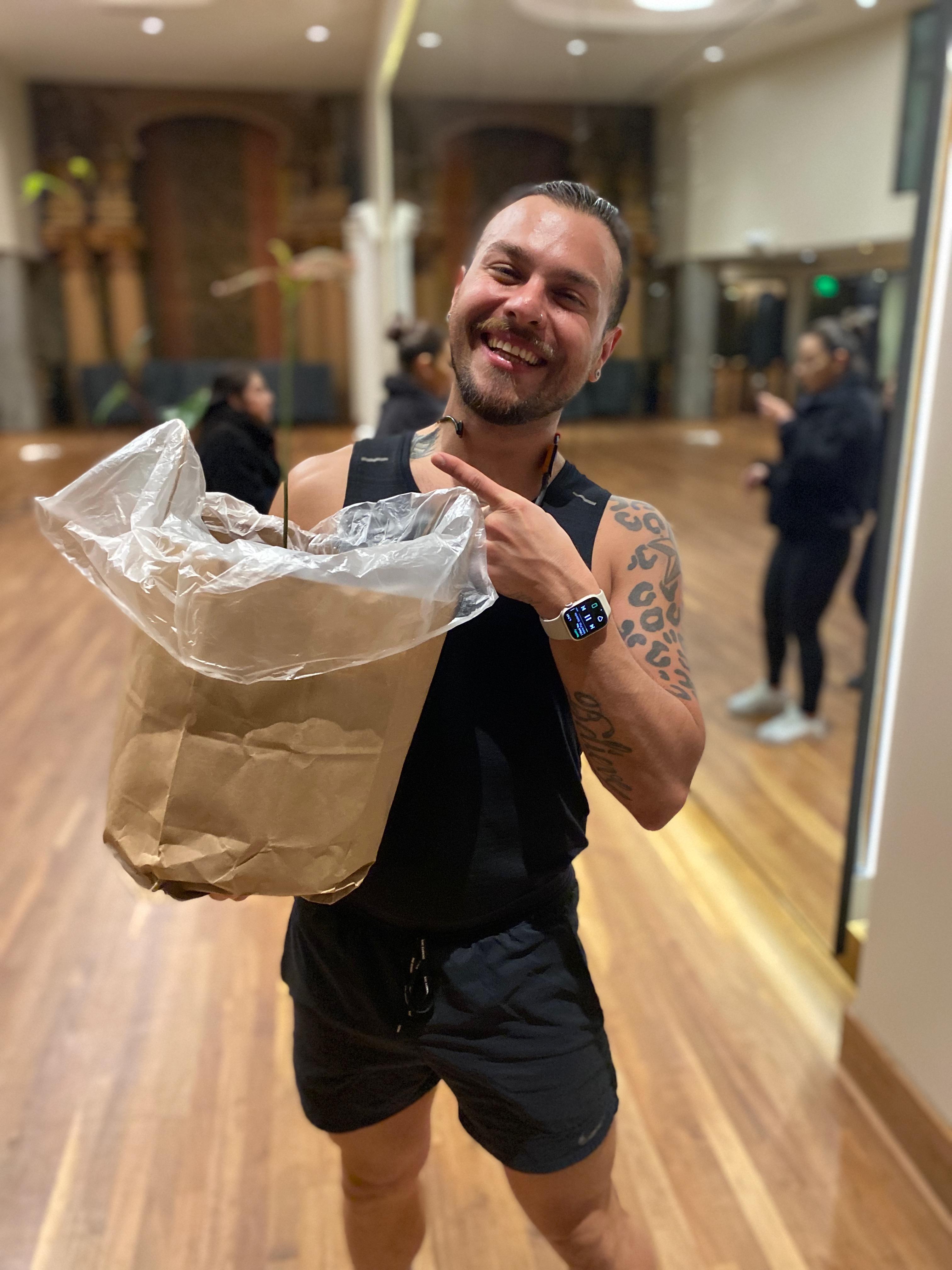 New plant parent smiling while holding a plant gifted by Reza Kaabi from Bank of Trees, ready to start their plant care journey.