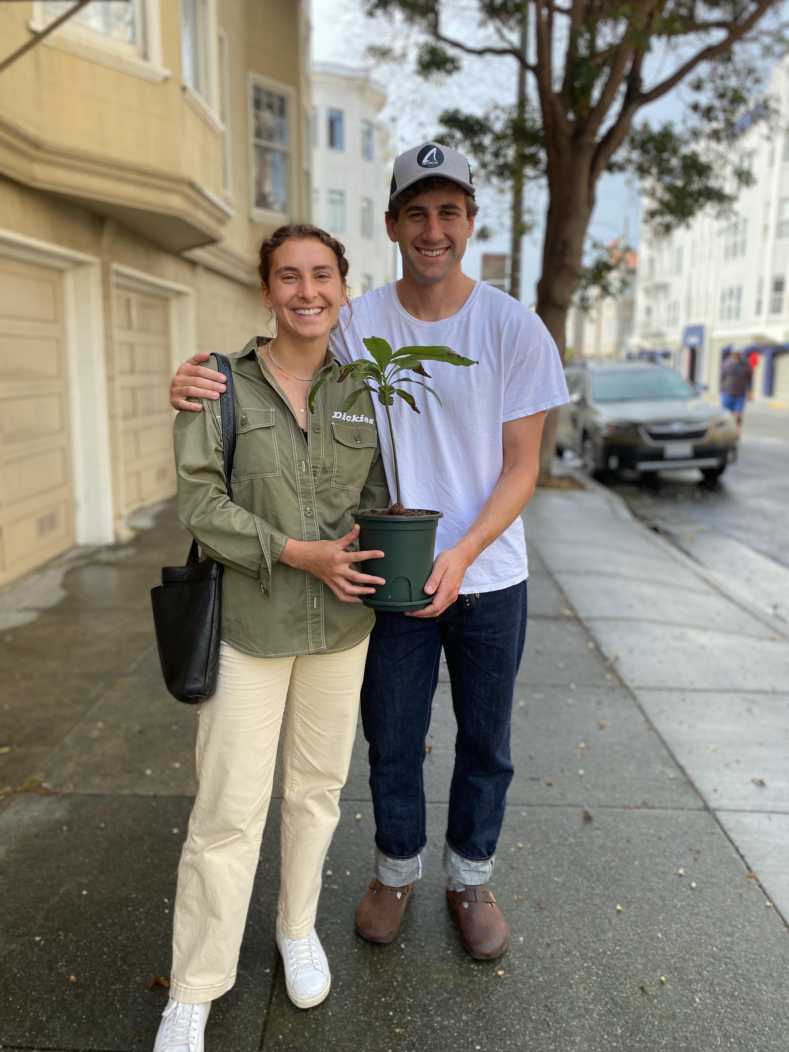 New plant parent smiling while holding a plant gifted by Reza Kaabi from Bank of Trees, ready to start their plant care journey.