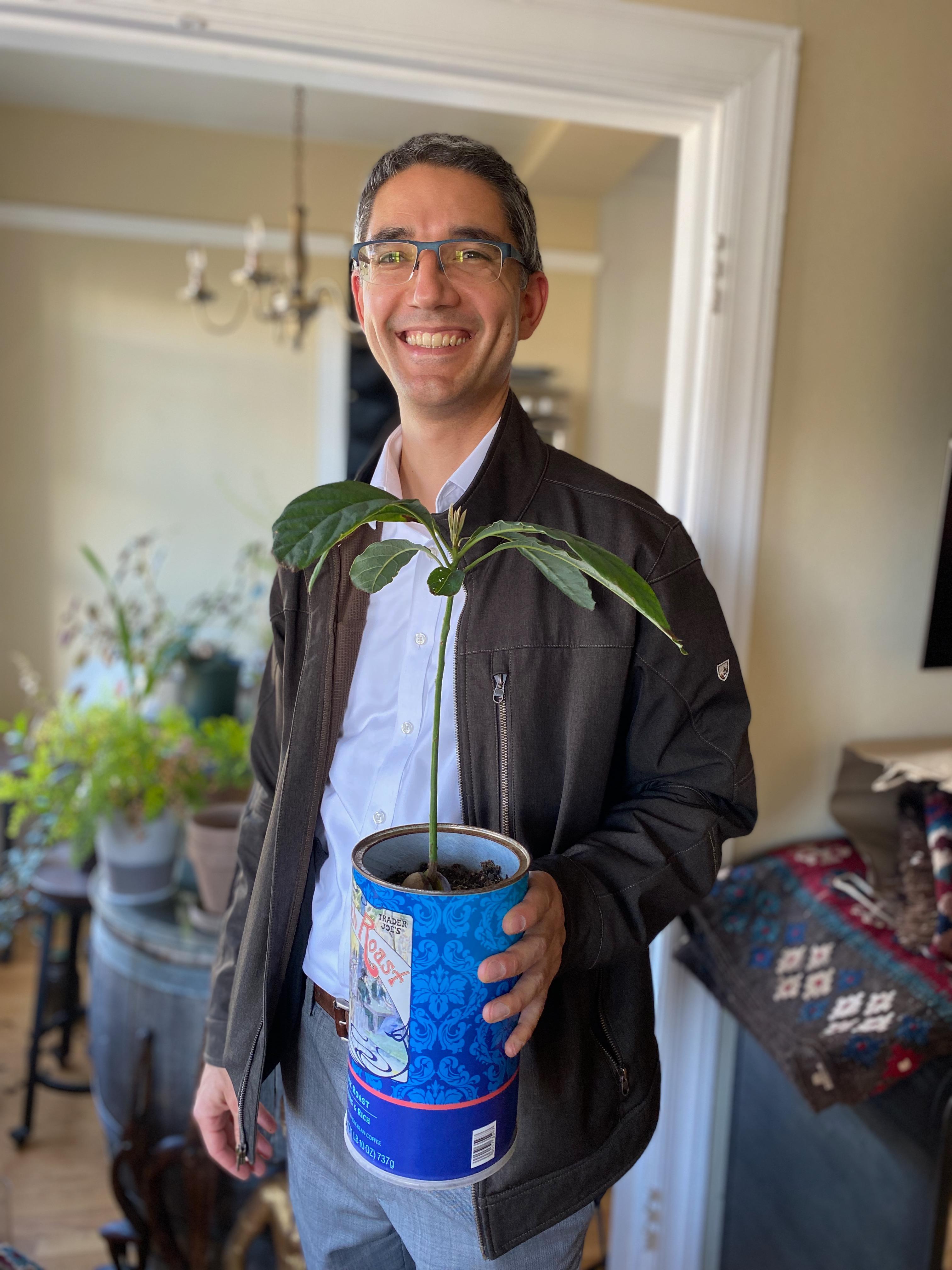 New plant parent smiling while holding a plant gifted by Reza Kaabi from Bank of Trees, ready to start their plant care journey.