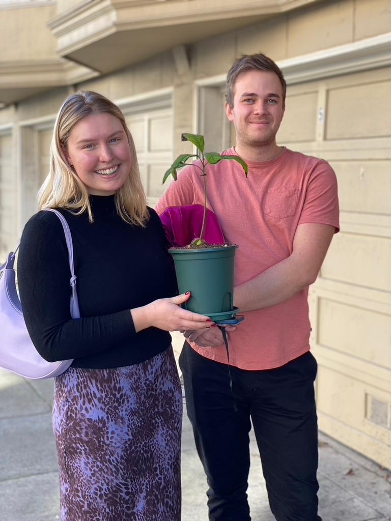 New plant parent smiling while holding a plant gifted by Reza Kaabi from Bank of Trees, ready to start their plant care journey.