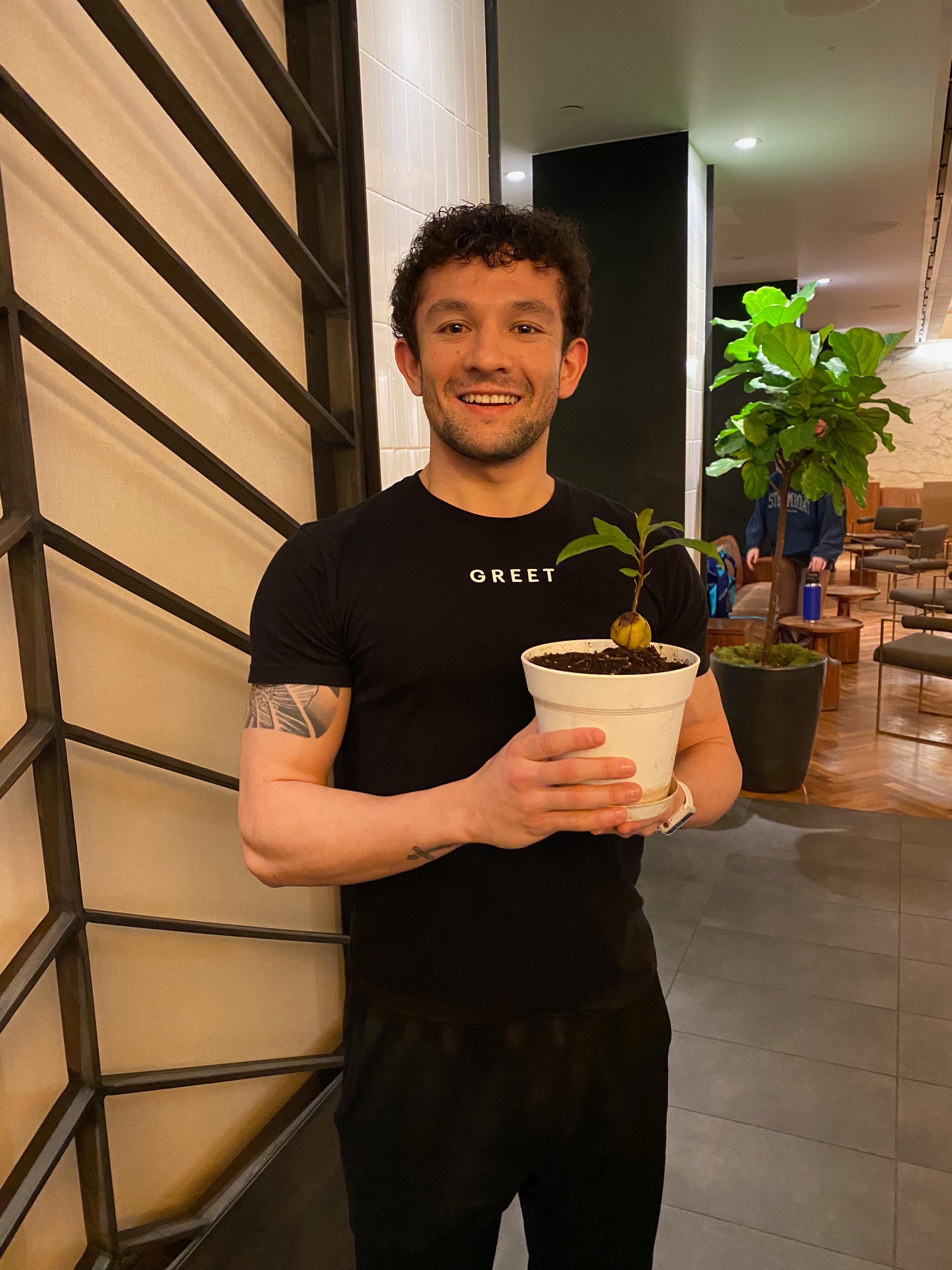 New plant parent smiling while holding a plant gifted by Reza Kaabi from Bank of Trees, ready to start their plant care journey.