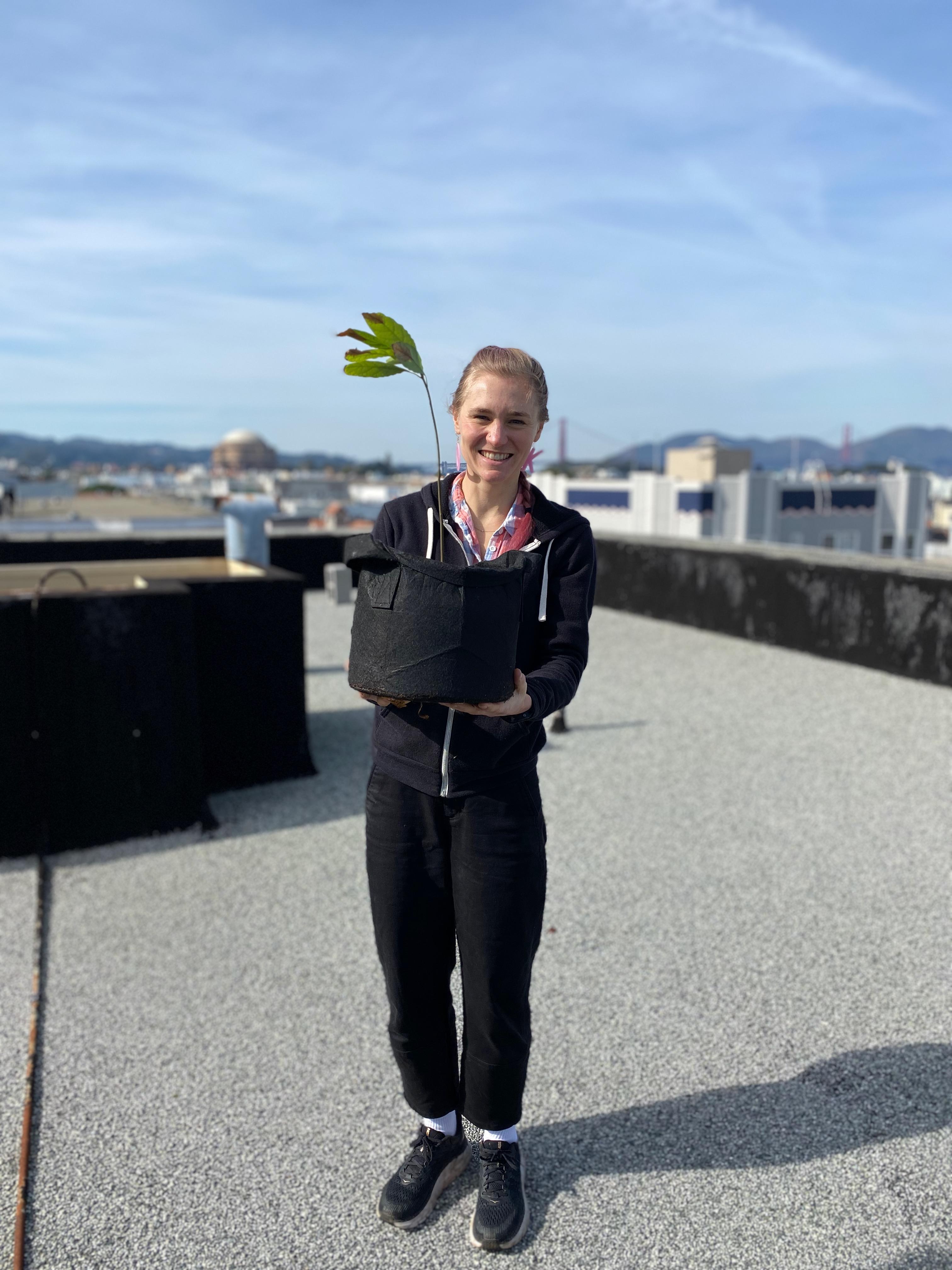 New plant parent smiling while holding a plant gifted by Reza Kaabi from Bank of Trees, ready to start their plant care journey.