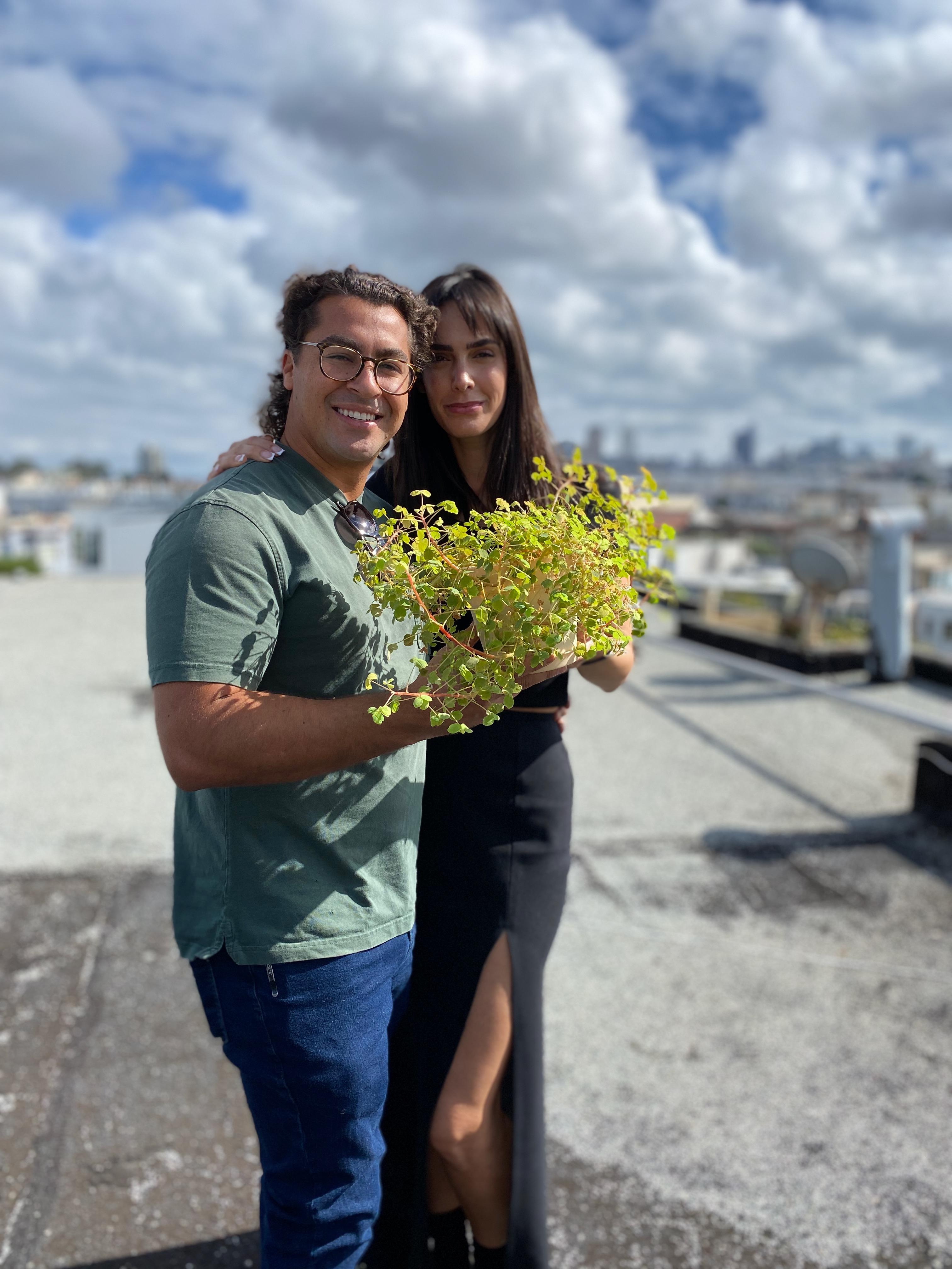 New plant parent smiling while holding a plant gifted by Reza Kaabi from Bank of Trees, ready to start their plant care journey.