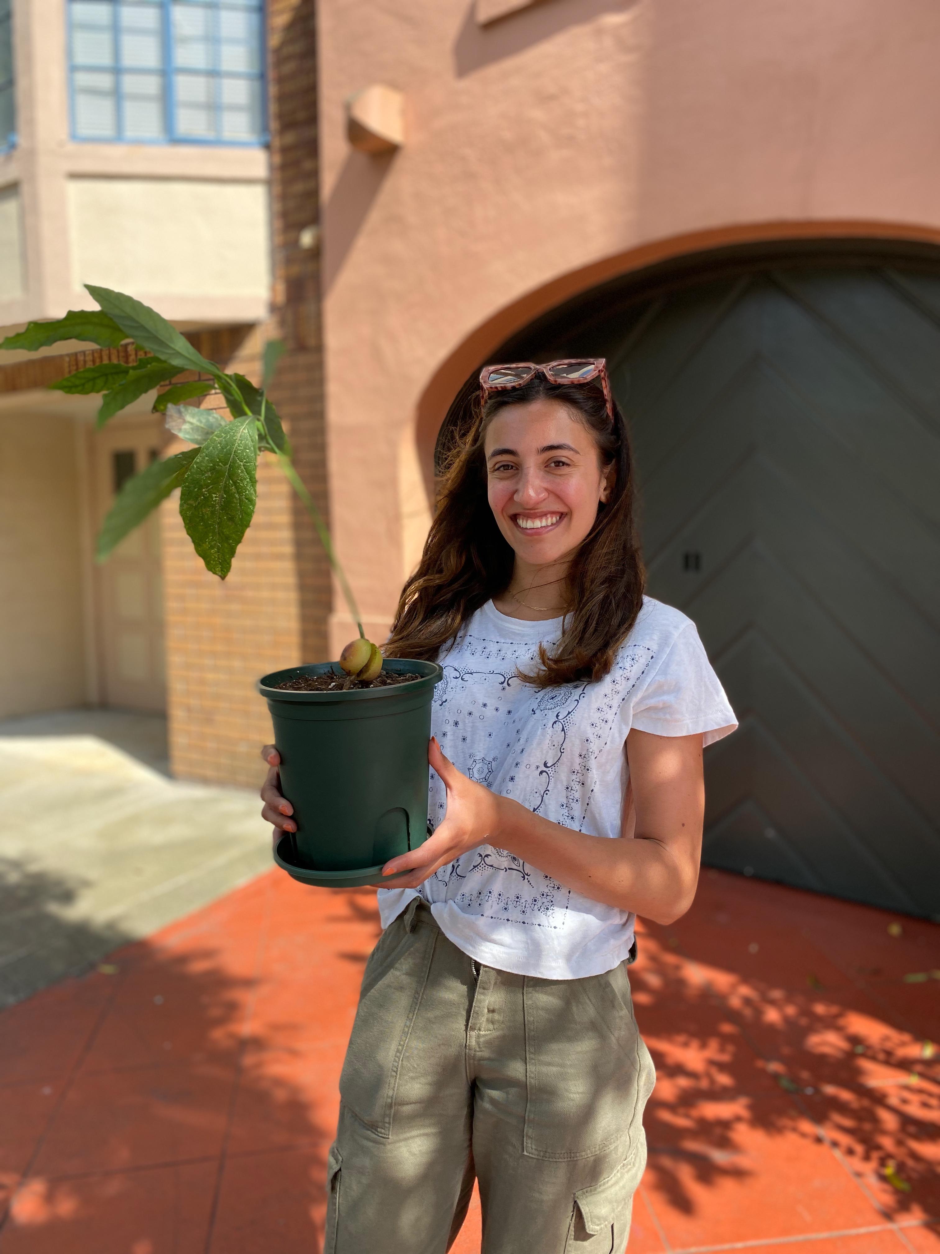 New plant parent smiling while holding a plant gifted by Reza Kaabi from Bank of Trees, ready to start their plant care journey.