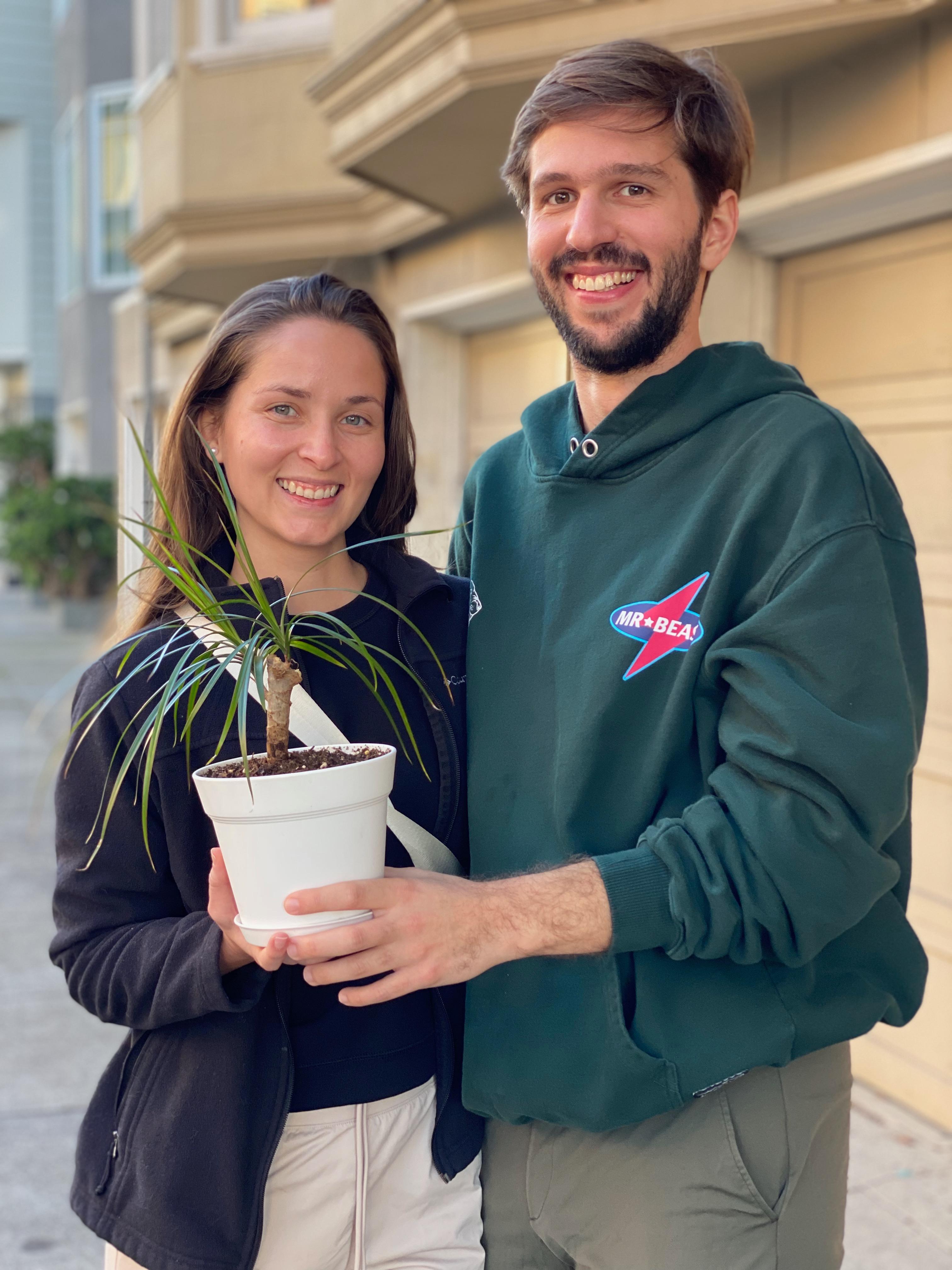 New plant parent smiling while holding a plant gifted by Reza Kaabi from Bank of Trees, ready to start their plant care journey.