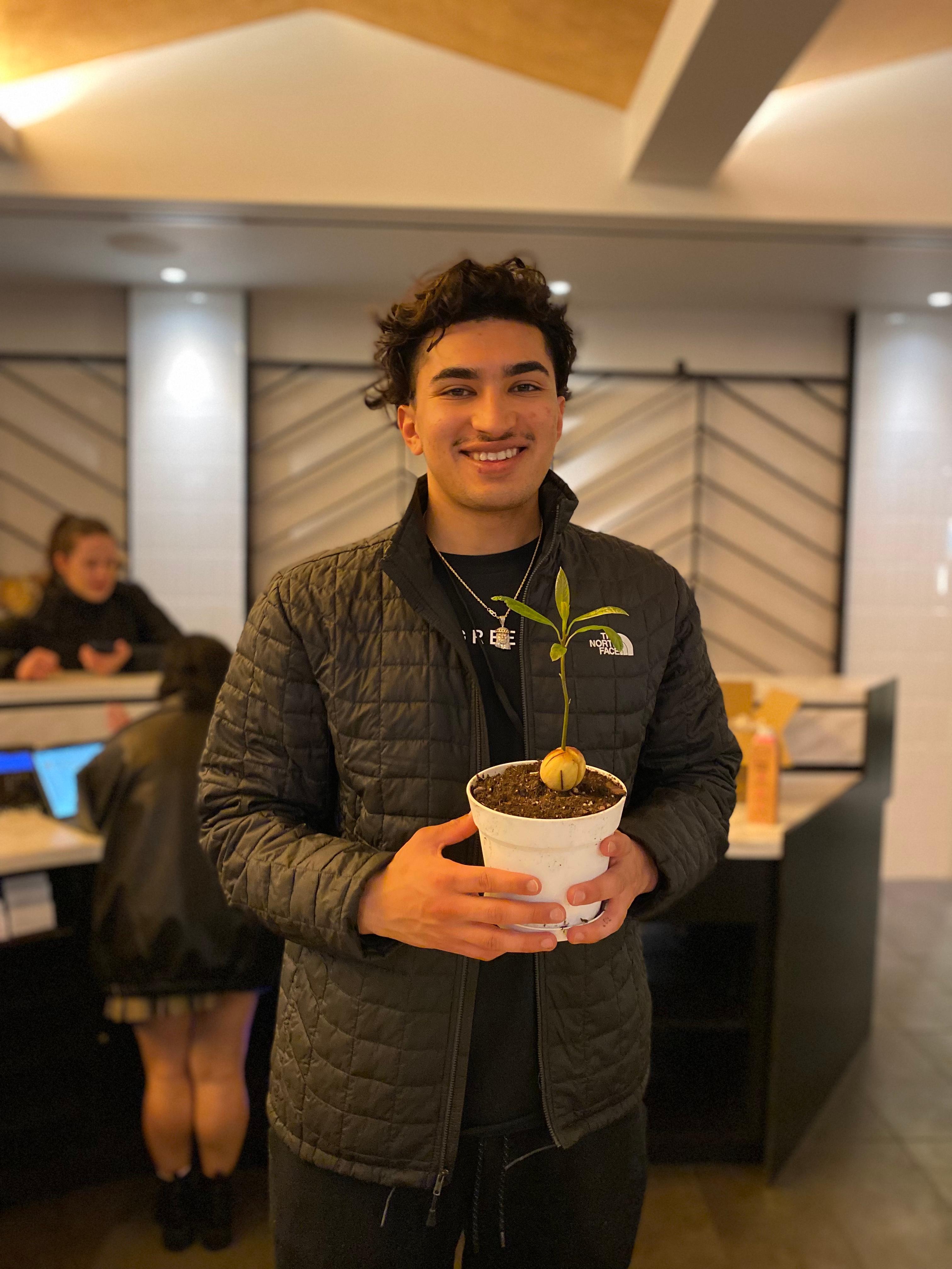 New plant parent smiling while holding a plant gifted by Reza Kaabi from Bank of Trees, ready to start their plant care journey.